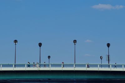 Low angle view of street lights on a bridge against blue sky