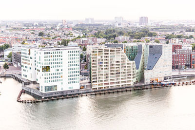 Buildings by river against sky in city