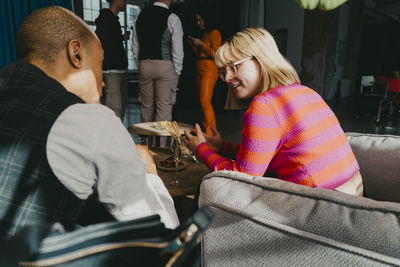 Blond businesswoman discussing with colleague sitting on couch during event at convention center