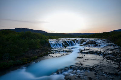 Scenic view of waterfall against sky during sunset