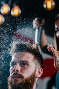 Close-up of woman spraying on man hair