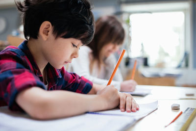 Mother and girl holding pencils on table