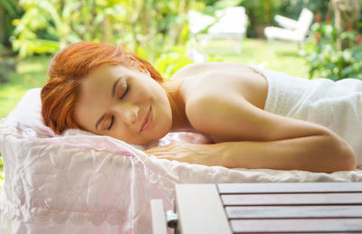 Smiling young woman sleeping on bed at spa