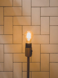 Close-up of illuminated light bulb against wall