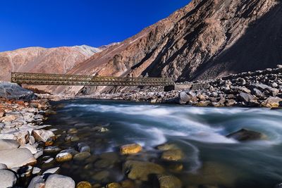 Bridge over shyok river against rocky mountains