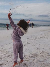 Full length of girl throwing sand while playing at beach