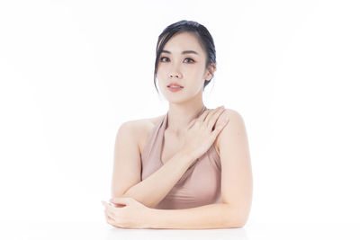 Portrait of young woman sitting against white background