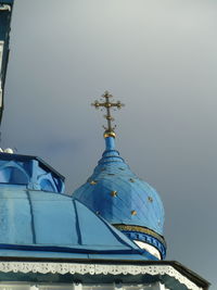 Low angle view of cross by building against sky