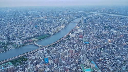 High angle view of illuminated city by river against buildings