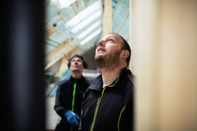 Coworkers in protective clothing looking up at construction site