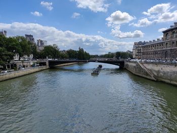 Arch bridge over river against cloudy sky