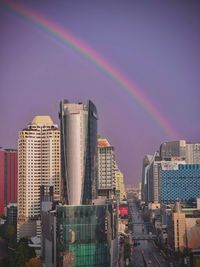 Rainbow over city buildings against sky