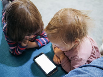 Two siblings watching something on a smartphone