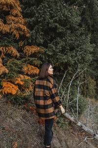 Young woman looking at autumn trees in forest