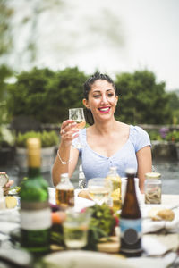 Smiling young woman looking away while enjoying wine at dinner party