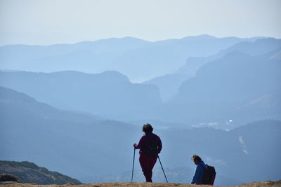 Rear view of men standing on mountain against sky