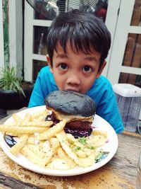 Portrait of cute boy with food on table at restaurant