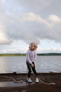 Girl standing on shore against sky