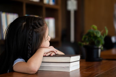 Close-up of girl with book on table at home