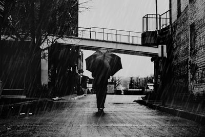 Rear view of man walking on wet street during monsoon