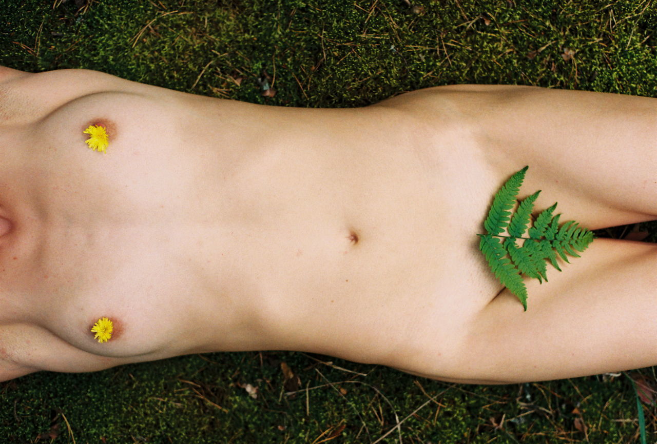 MIDSECTION OF WOMAN LYING DOWN ON GRASS