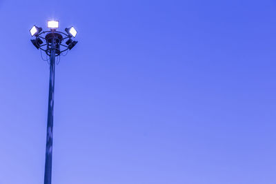 Low angle view of illuminated street light against blue sky