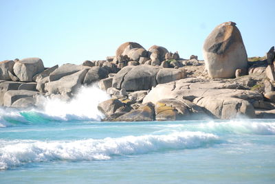 Rocks in sea against clear sky