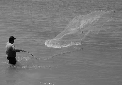 Rear view of man fishing in sea