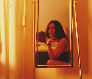 Portrait of young woman reflecting on mirror at home