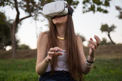 Young woman using virtual reality simulator while enjoying at park