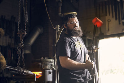 Blacksmith holding red hot metal with tongs in workshop