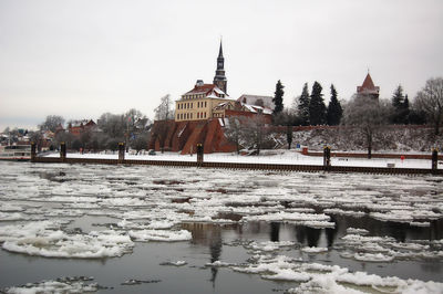 View of frozen river with trees in background