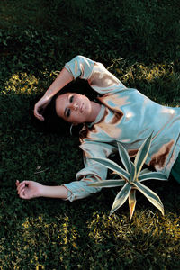 High angle portrait of young woman lying on land in park