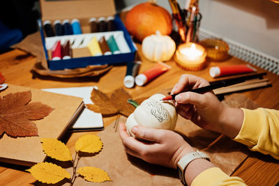 Autumn pumpkins craft. diy fall crafts for adults. female hands draw patterns on white pumpkin
