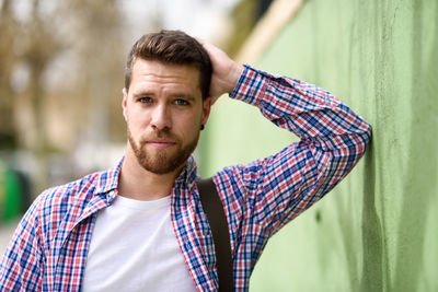 Portrait of young man standing by green wall