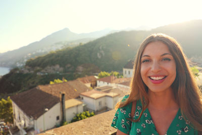 Portrait of smiling young woman on mountain against sky