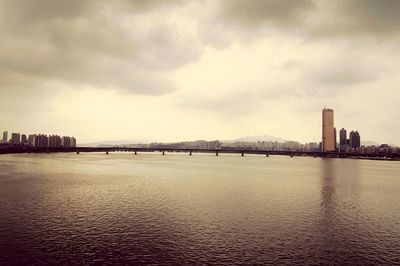 Bridge over river in city against sky