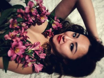 High angle portrait of smiling young woman lying on bed