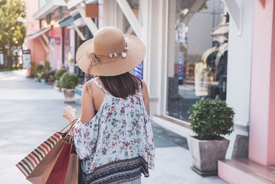 Rear view of woman with umbrella standing on street