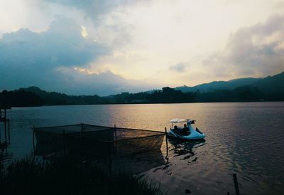 Boat moored on lake against sky