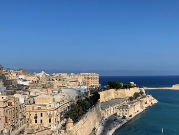 High angle view of buildings by sea against clear sky