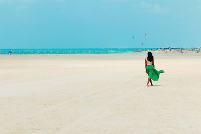 Man standing on beach against clear blue sky