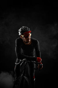 Side view of man riding bicycle against black background
