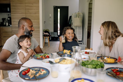 Happy family enjoying breakfast while sitting together on dining table at home
