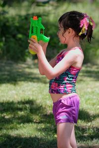 Midsection of girl holding purple flower on field