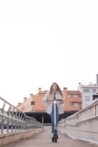 Young beautiful woman looking at the camera going down the ramp in her new electric scooter