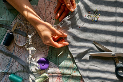Woman is sketching pattern on a linen fabric seamstress basting and sewing. sartorial clothes. 