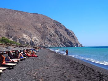 People on beach against blue sky
