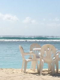 Chairs on beach against sky