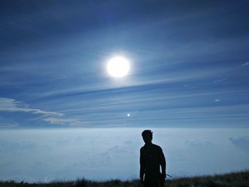 Silhouette of man against sun in sky